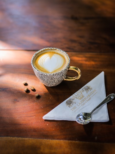 Brown wooden table in the black and white ceramic cup with a silver spoon
